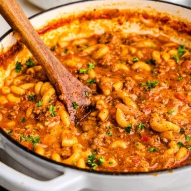 Old Fashioned American Goulash in a white cast iron pot.