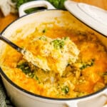 A ladle full of One Pot Chicken Broccoli & Rice in a white cast iron pot.