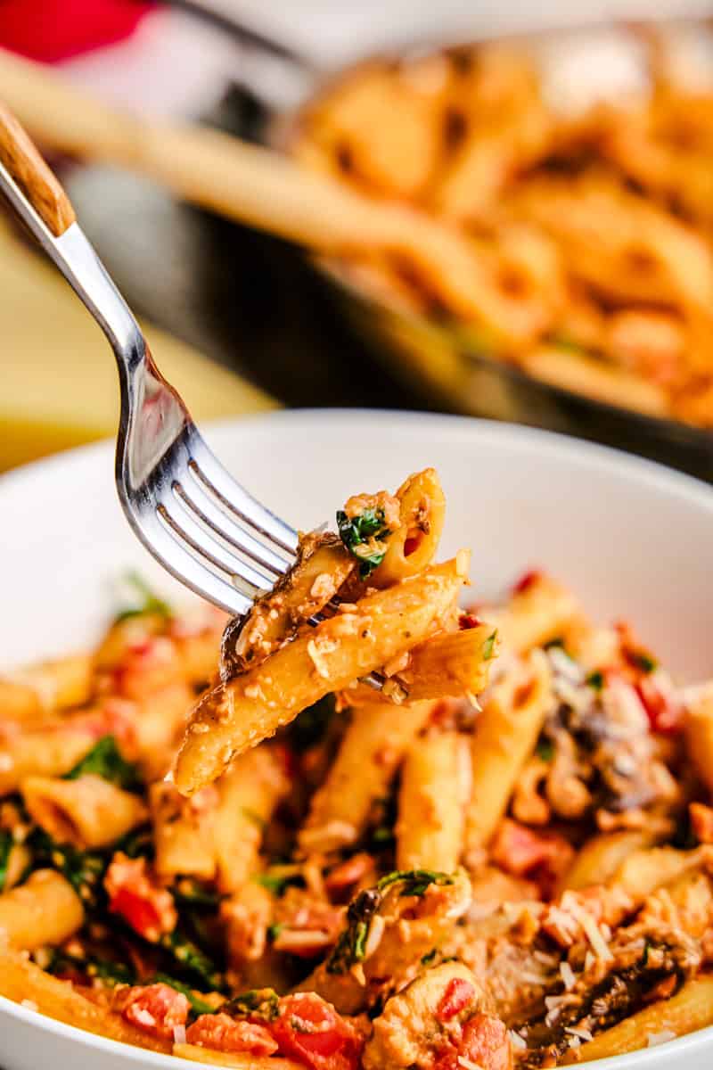 A forkful of Penne Rosa hovering over a bowl of pasta.