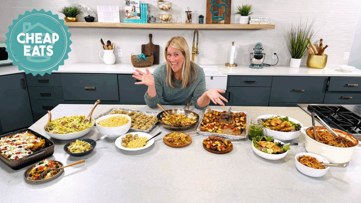A photo of Chef Cayt in The Stay At Home Chef Kitchen with the meals from Week 2 of the Cheap Eats Meal plan on display on the kitchen counter.