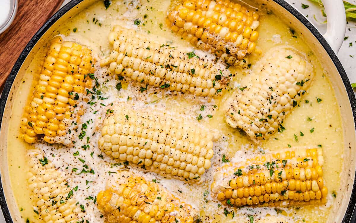 An overhead of Butter Boiled Corn on the Cob in a cast iron pot.