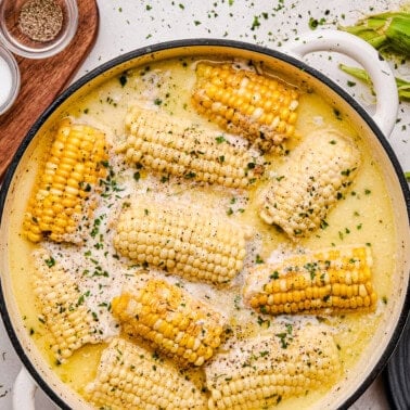 An overhead of Butter Boiled Corn on the Cob in a cast iron pot.