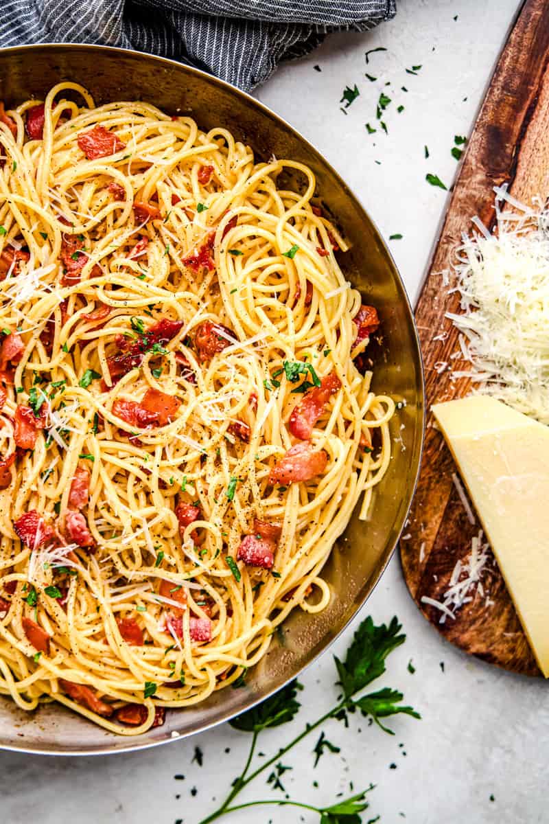 Eggless Spaghetti Carbonara in a pan topped with parmesan and parsley.