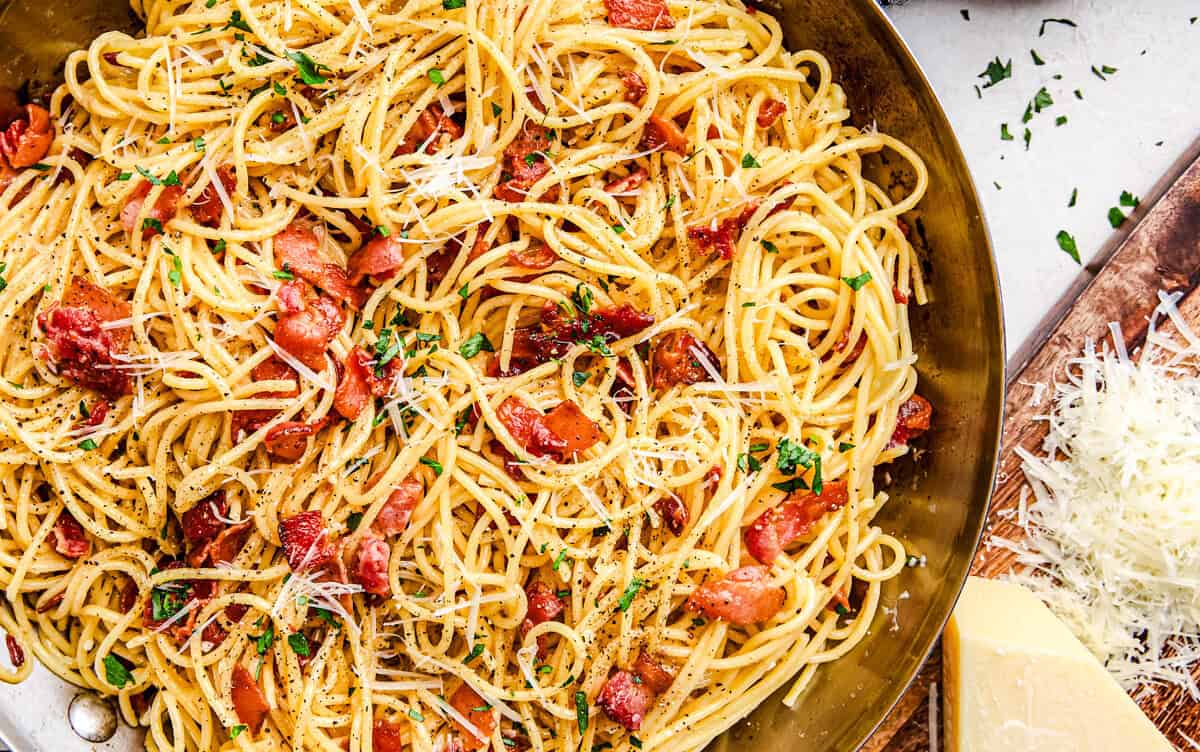 Eggless Spaghetti Carbonara in a pan topped with parmesan and parsley.