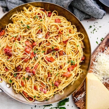 Eggless Spaghetti Carbonara in a pan topped with parmesan and parsley.