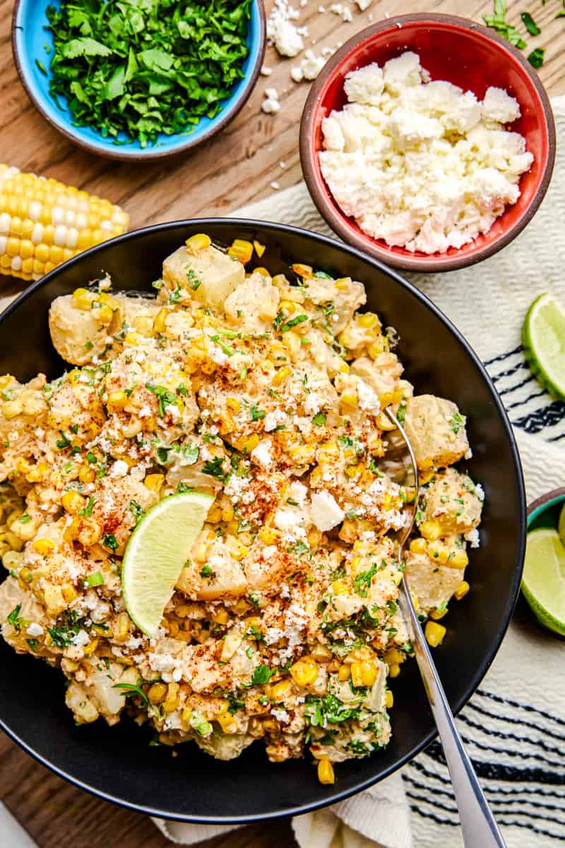 Mexican Street Corn Potato Salad in a black bowl with lime wedge.