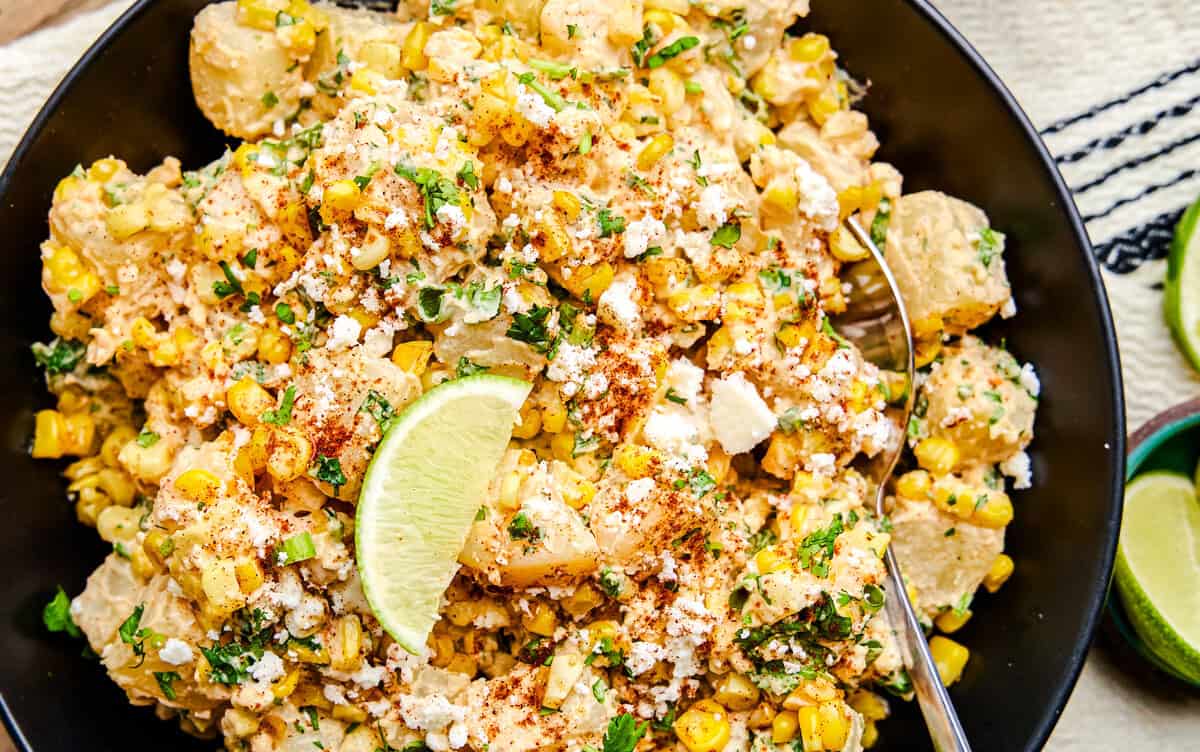 Mexican Street Corn Potato Salad in a black bowl with lime wedge.