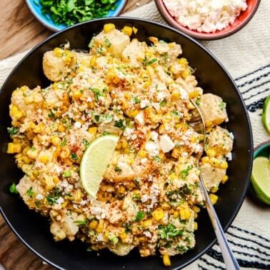 Mexican Street Corn Potato Salad in a black bowl with lime wedge.