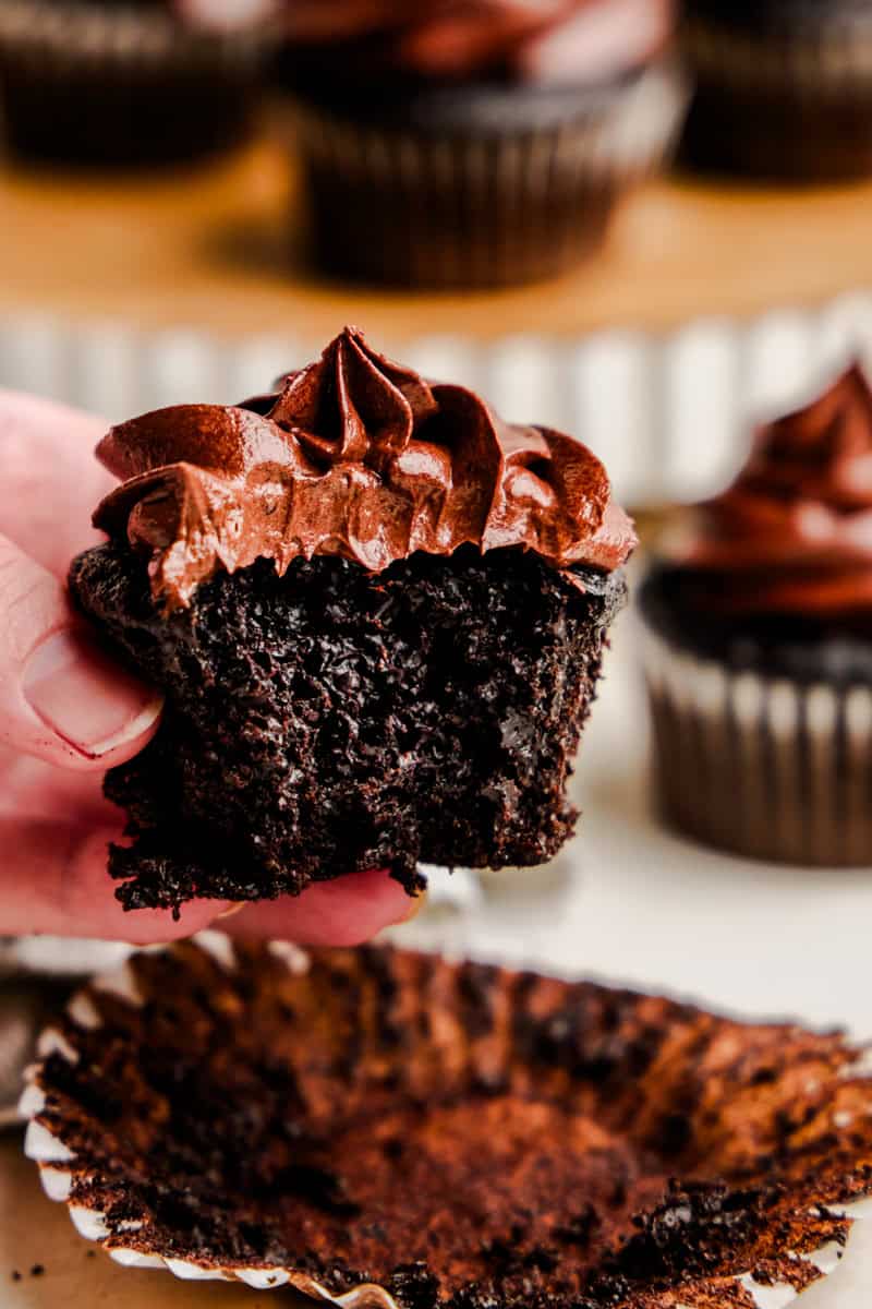 A hand holding The Most Amazing Chocolate Cupcake with a bite taken out of it.