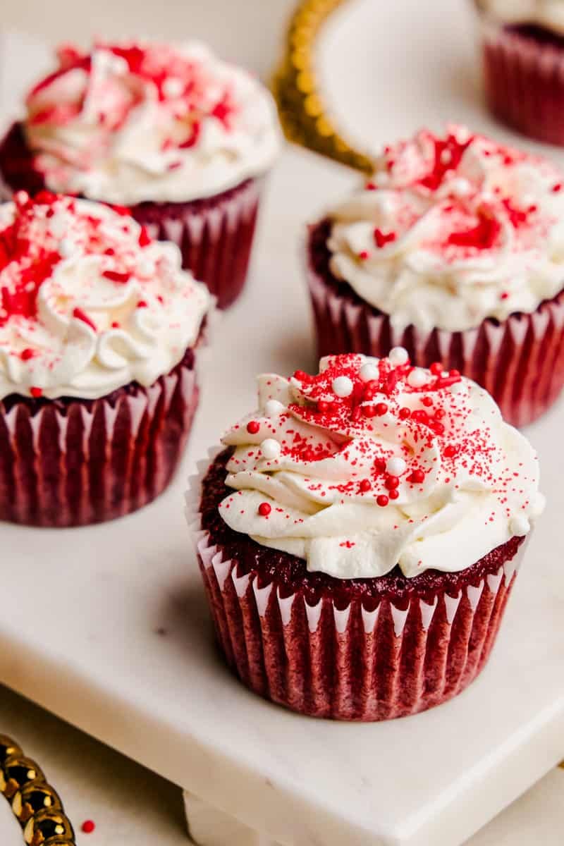 The Most Amazing Red Velvet Cupcakes lined up on a tray and decorated with red sprinkles.
