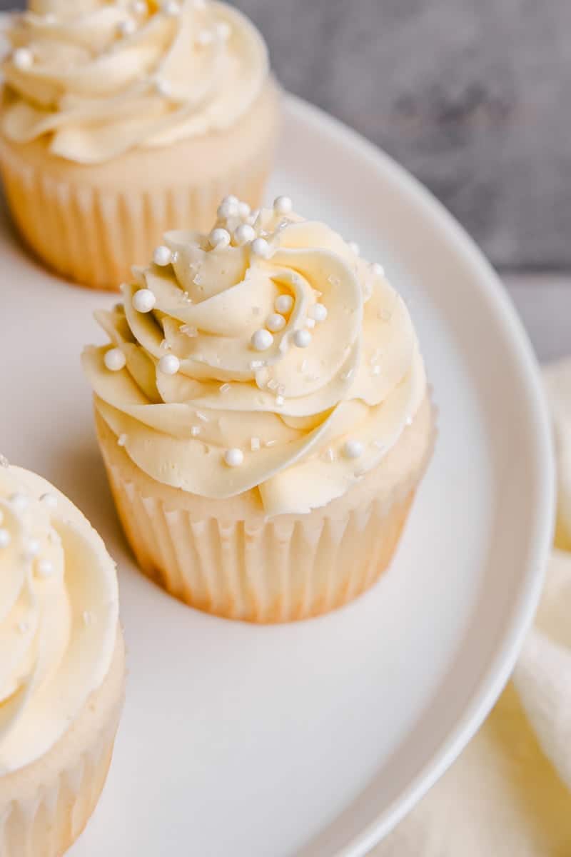 A Cake stand full of the Most Amazing White Cupcakes with crystal sugar and white sprinkles.