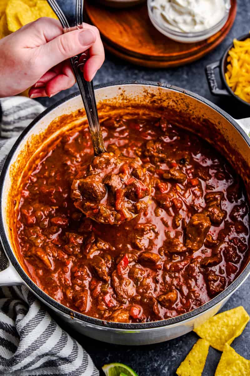 A ladle full of No Bean Chili over a cast iron pot.