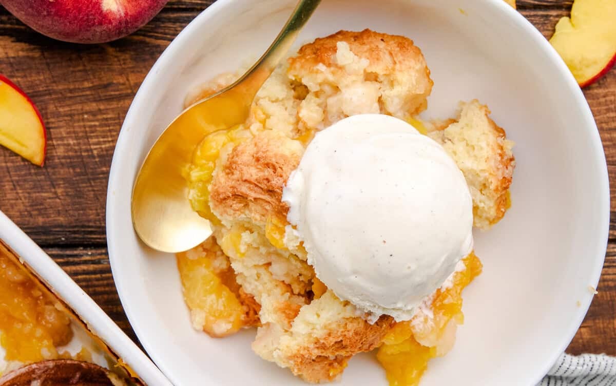 A bowl full Old Fashioned Peach Cobbler topped with ice cream.