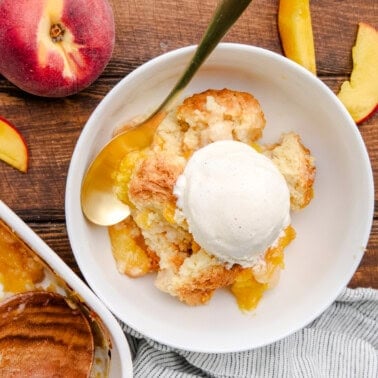 A bowl full Old Fashioned Peach Cobbler topped with ice cream.