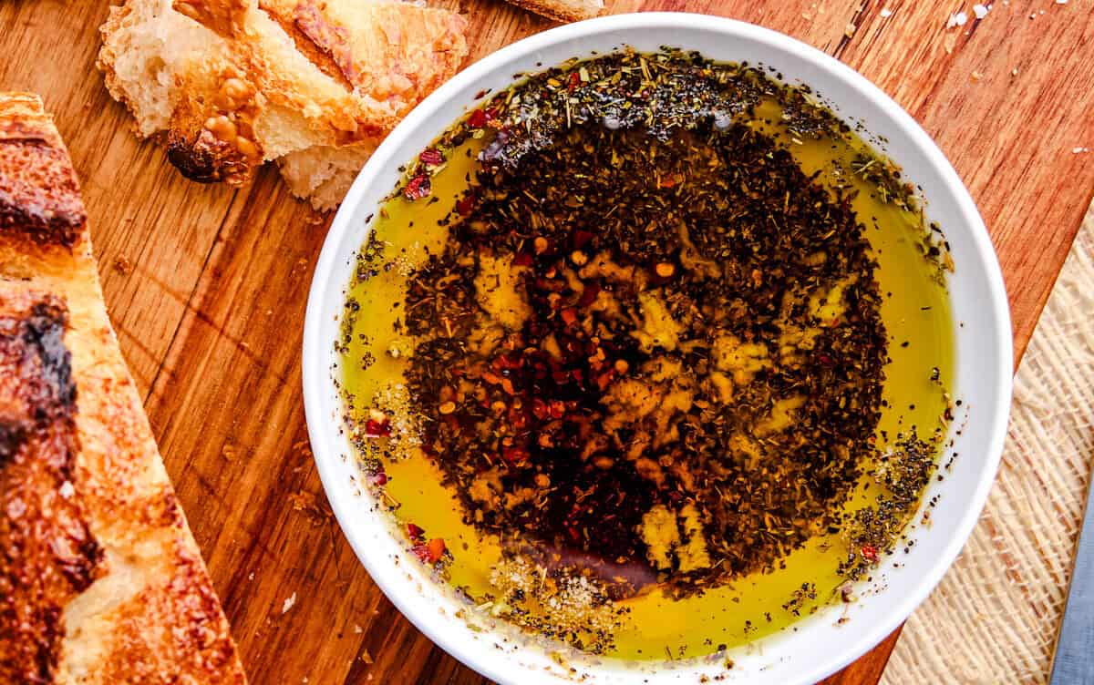 Olive Oil Bread Dip on a cutting board with fresh bread pieces around.