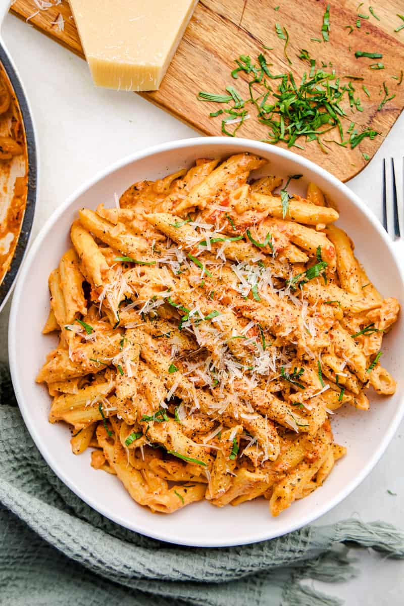 An overhead image Penne Alla Vodka in a bowl topped with parmesan and basil.