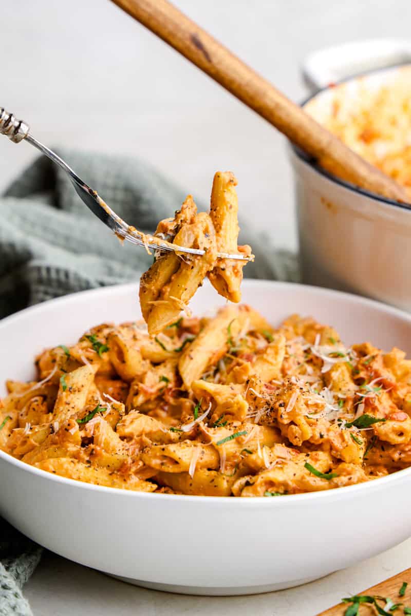 A forkful of Penne Alla Vodka hovering above a bowl.