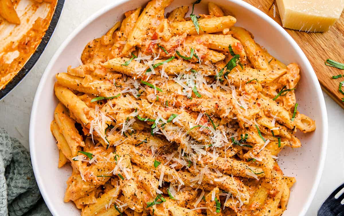 An overhead image Penne Alla Vodka in a bowl topped with parmesan and basil.