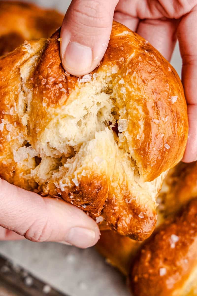 Hands pulling apart a freshly baked Soft Pretzel to show the fluffy inside.