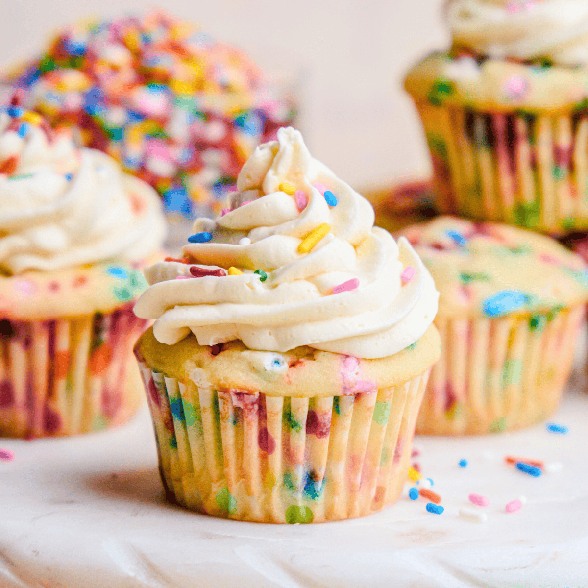 A Funfetti Birthday Cupcake on a cake stand with sprinkles.
