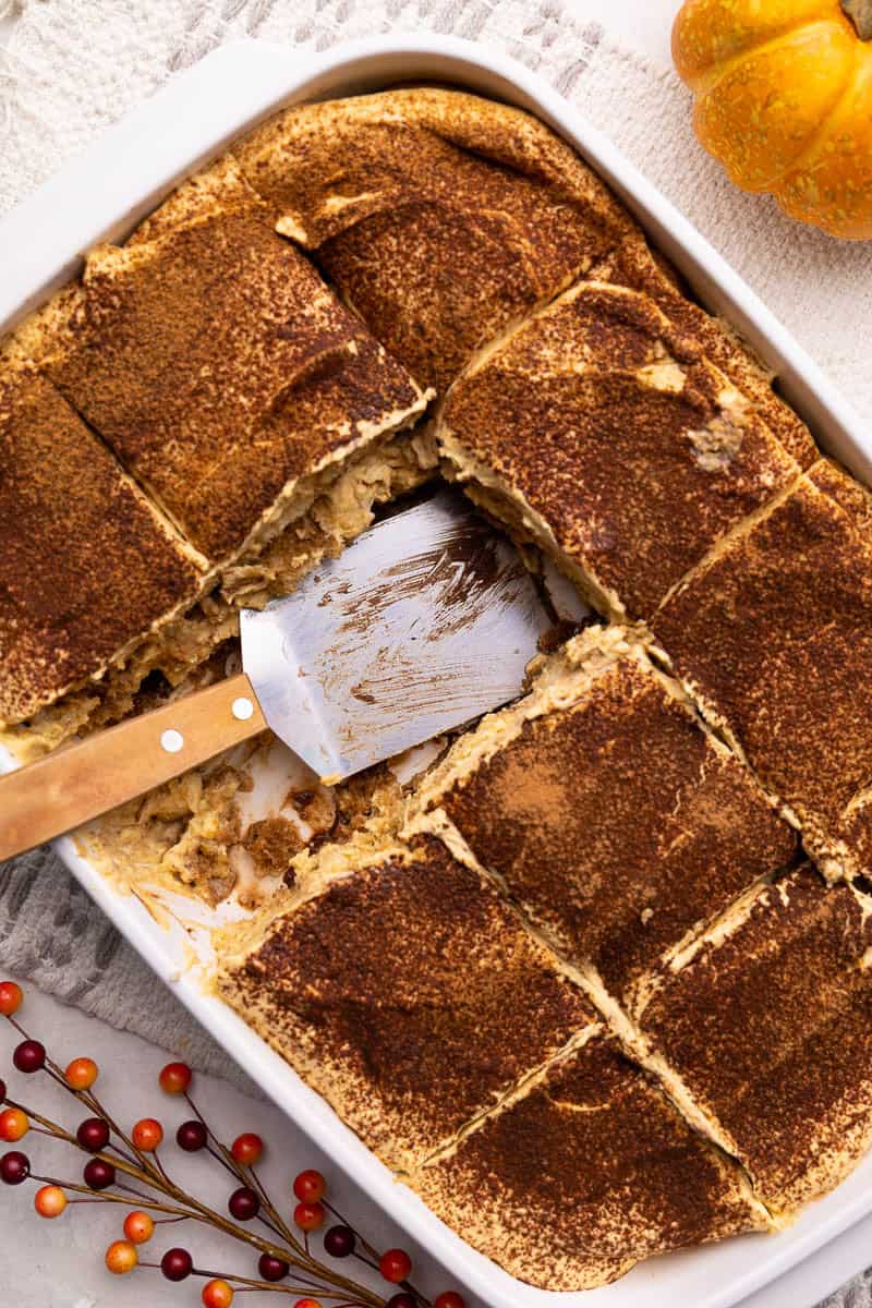 An overhead view of pumpkin latte tiramisu with a slice taken out. The serving spatula is left resting in the pan.