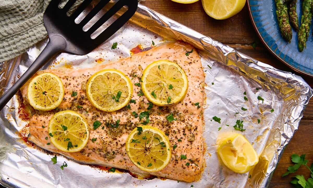 Easy Garlic Herb Baked Salmon topped with lemons on a sheet pan.