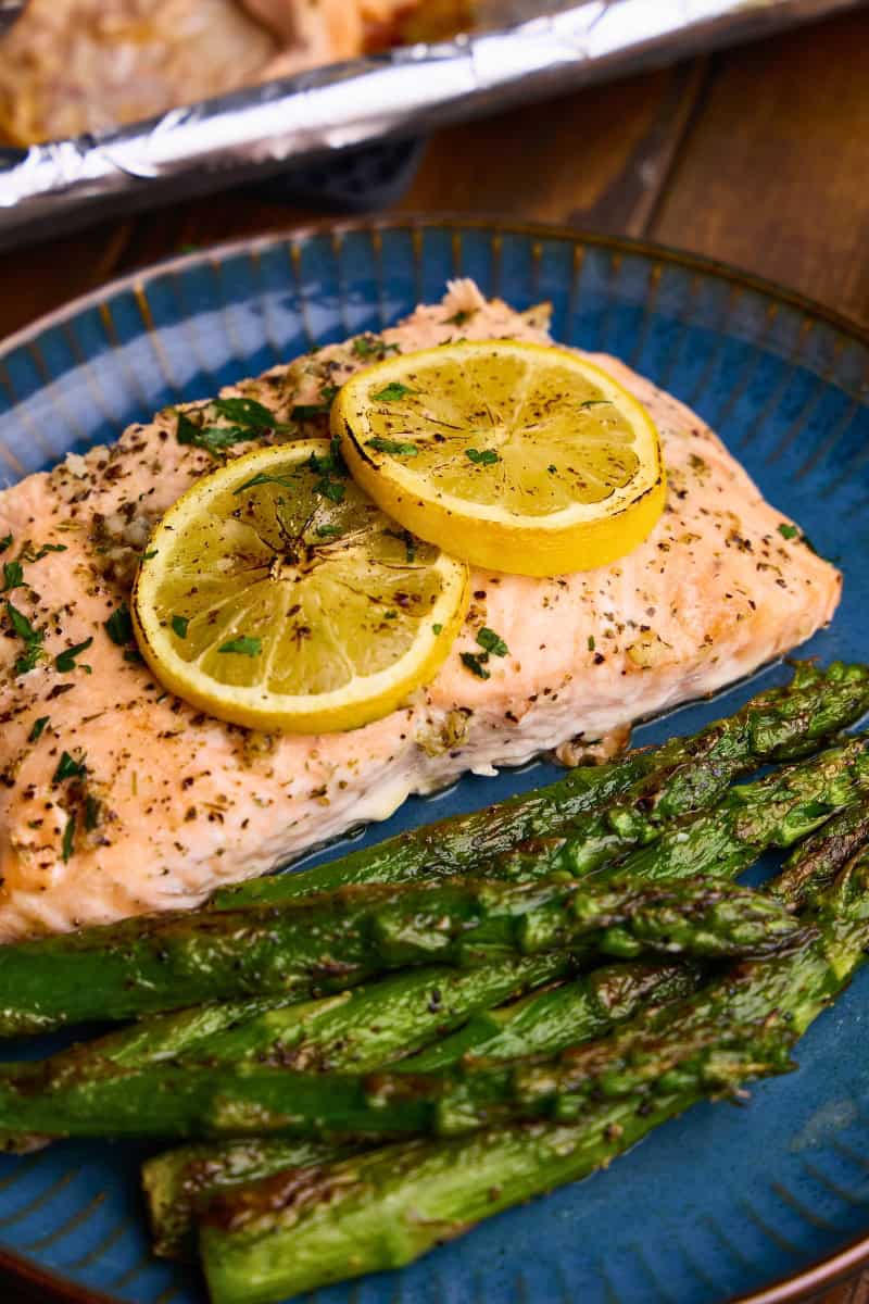 A piece of Easy Garlic Herb Baked Salmon on a plate with asparagus.