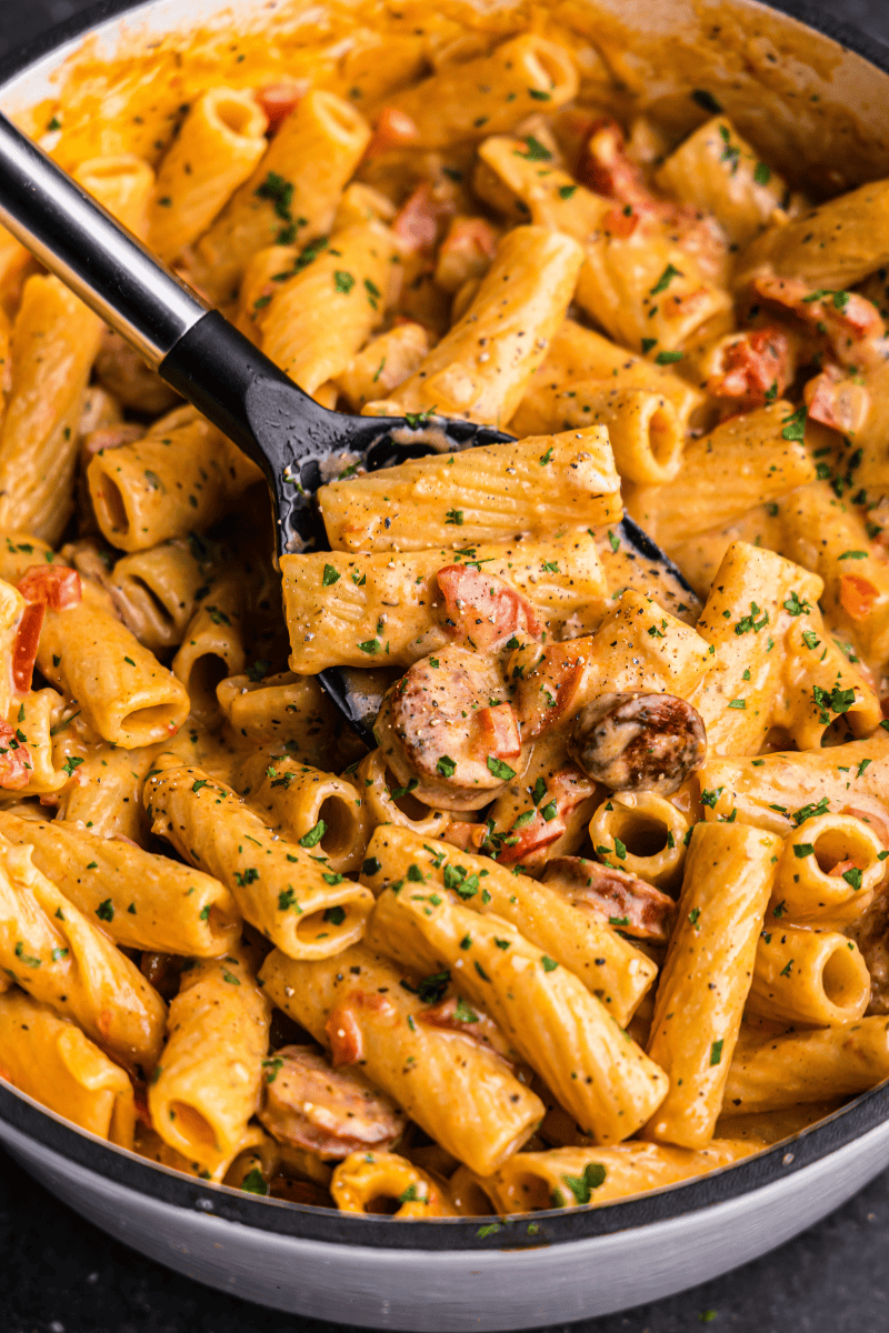 A closeup view of a pot of creamy cajun sausage pasta with andouille sausage.