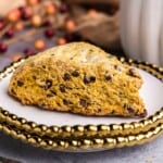 A closeup view of a pumpkin chocolate chip scone on a stack of two plates.