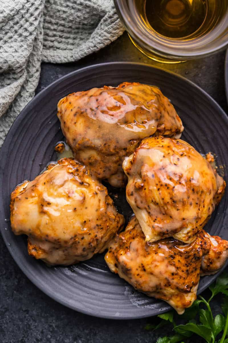 An overhead view of 4 apple cider glazed chicken thighs on a black plate.