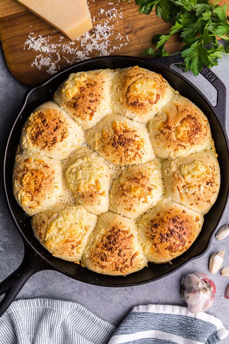An overhead view of a cast iron skillet of cheesy garlic butter pull apart rolls.