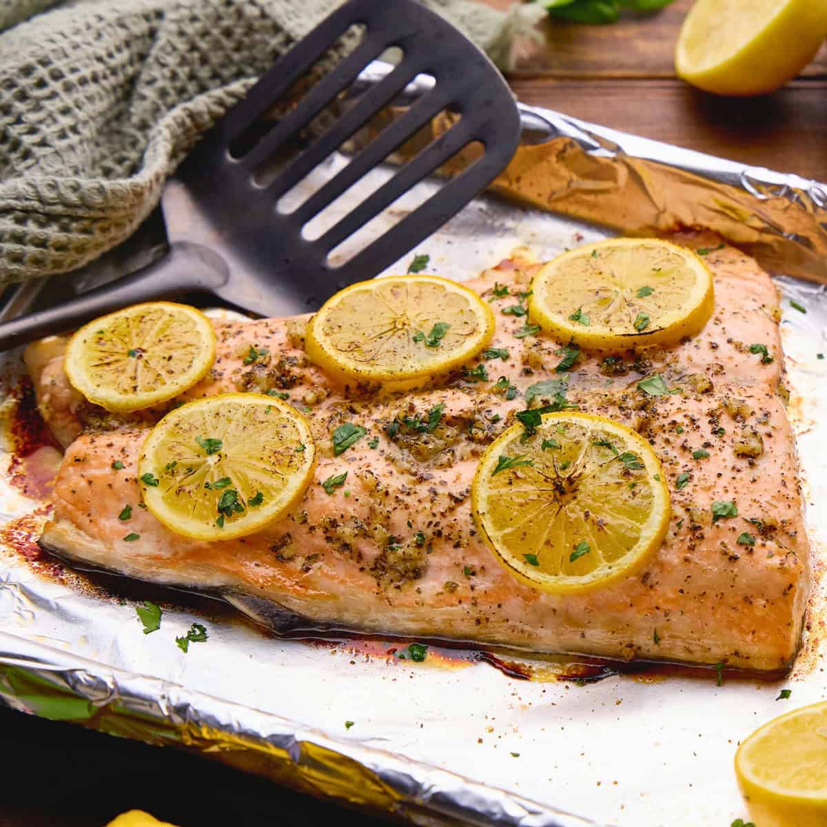 Easy Garlic Herb Baked Salmon topped with lemons on a sheet pan.