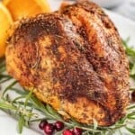 Golden brown oven roasted turkey breast on a platter, garnished with fresh herbs.