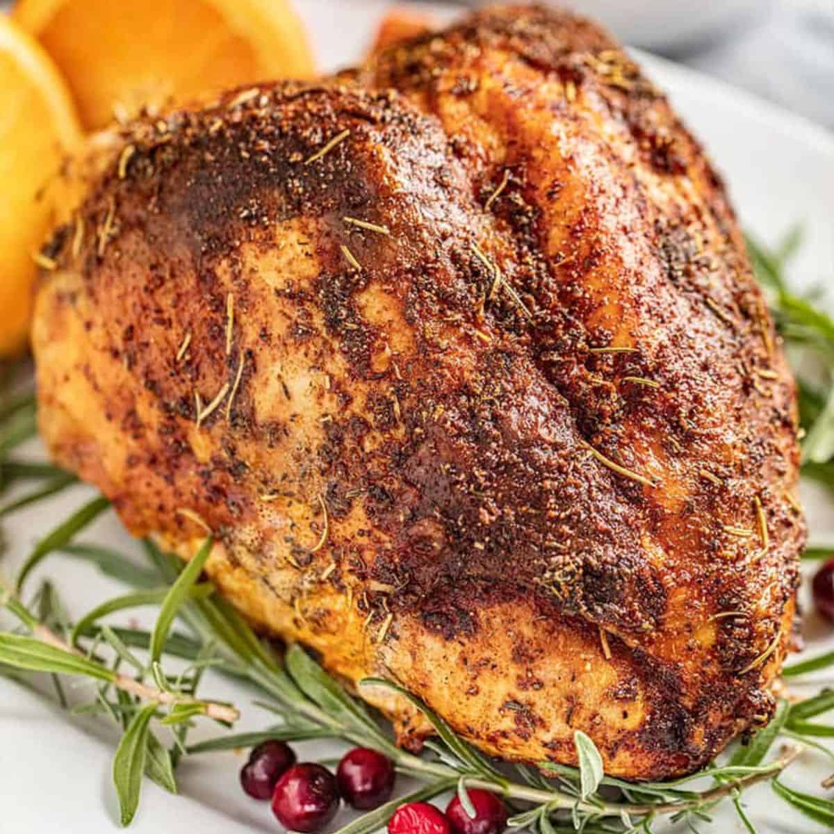 Golden brown oven roasted turkey breast on a platter, garnished with fresh herbs.