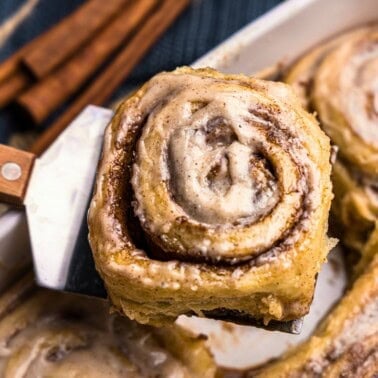 A chai latte sweet roll being lifted out of the pan with a spatula.