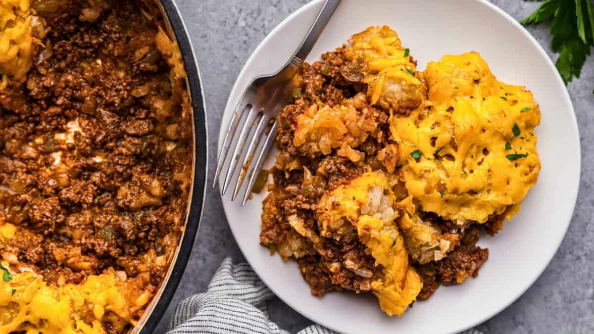 An overhead view of a plate of tater tot casserole with the rest of the pan nearby.